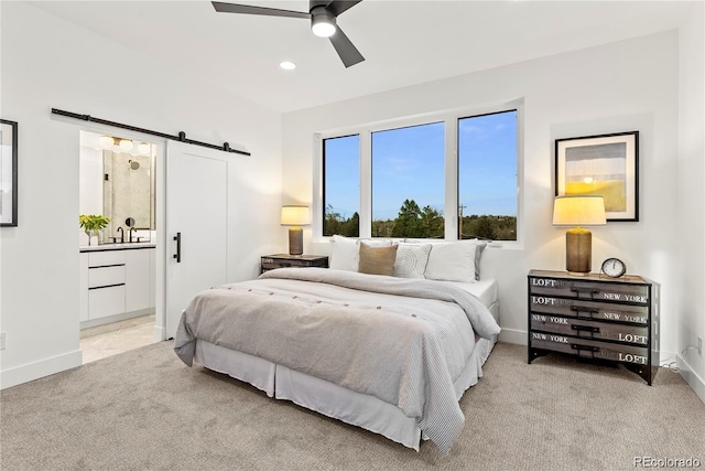 bedroom featuring carpet, connected bathroom, baseboards, and a barn door