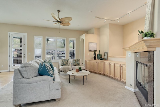 living room featuring rail lighting, ceiling fan, a tiled fireplace, and a healthy amount of sunlight