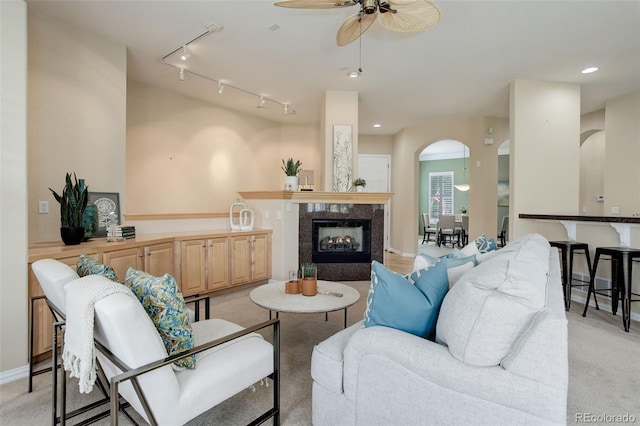 carpeted living room with a tiled fireplace, rail lighting, and ceiling fan