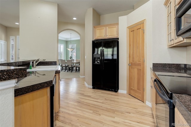 kitchen with sink, black appliances, light brown cabinetry, and light hardwood / wood-style flooring