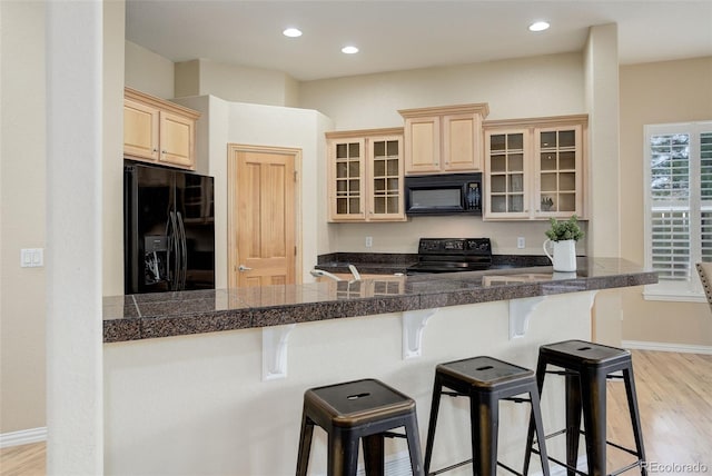 kitchen featuring kitchen peninsula, black appliances, and a breakfast bar