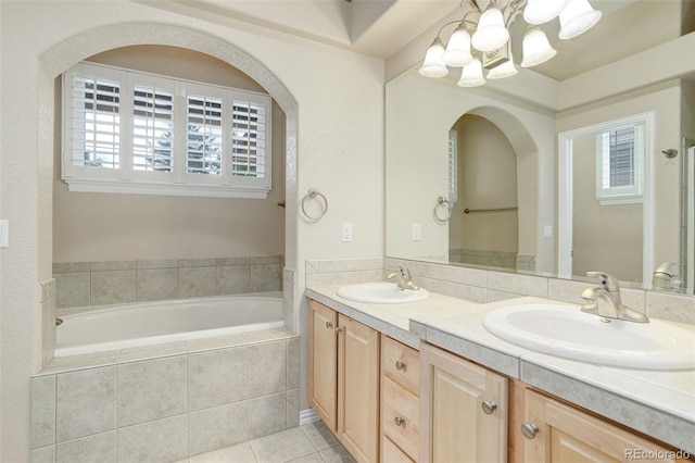 bathroom featuring tiled bath, vanity, and tile patterned flooring