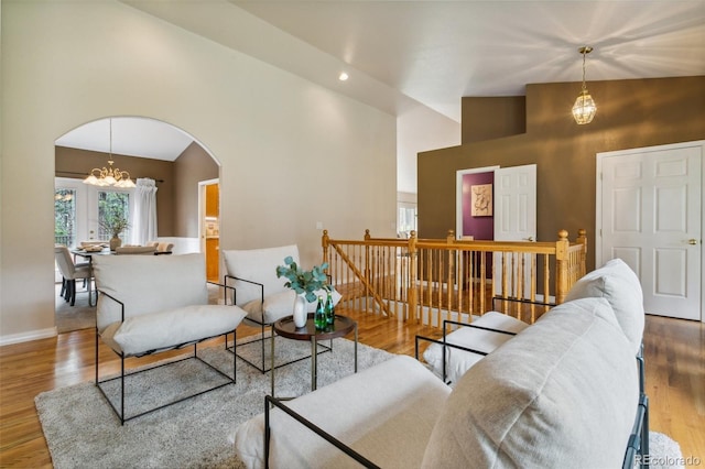 19770 Roaming Dr, Colorado Springs, CO 80908 - living room with arched walkways, a chandelier, wood finished floors, and high vaulted ceiling