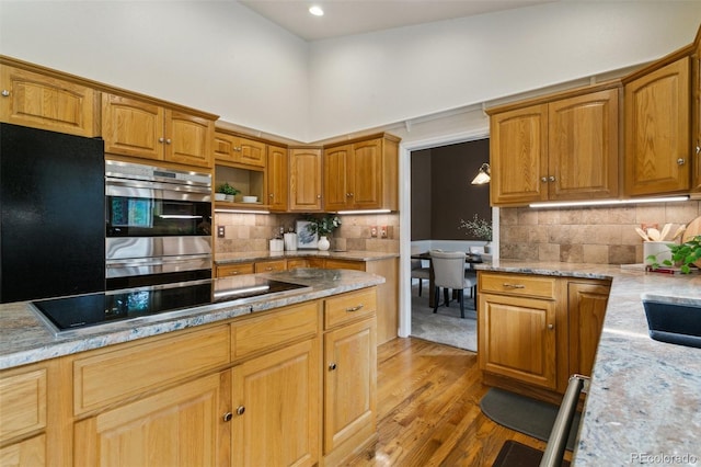 19770 Roaming Dr, Colorado Springs, CO 80908 - kitchen featuring black electric cooktop, light wood-type flooring, decorative backsplash, light stone counters, and a high ceiling