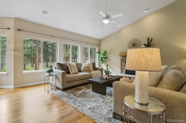19770 Roaming Dr, Colorado Springs, CO 80908 - living area featuring wood finished floors, lofted ceiling, healthy amount of natural light, ceiling fan, and a stone fireplace