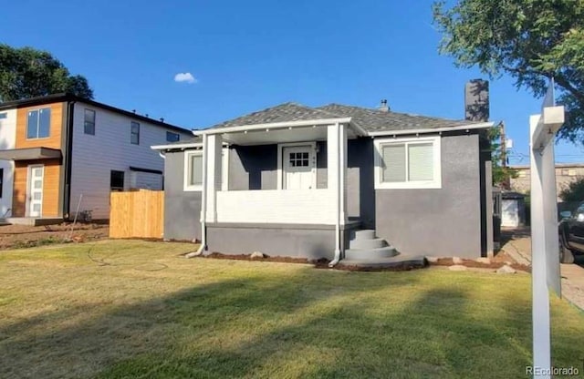 view of front of home with a front yard, fence, a chimney, and stucco siding