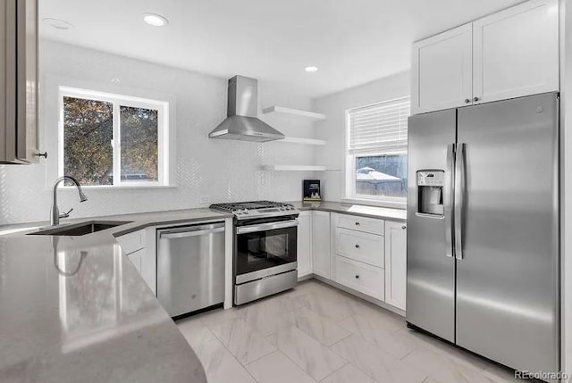 kitchen with white cabinets, marble finish floor, stainless steel appliances, wall chimney exhaust hood, and a sink