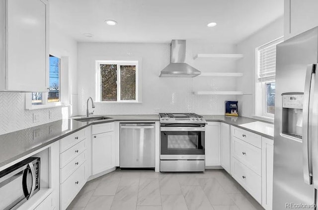 kitchen with a sink, wall chimney range hood, white cabinetry, and stainless steel appliances