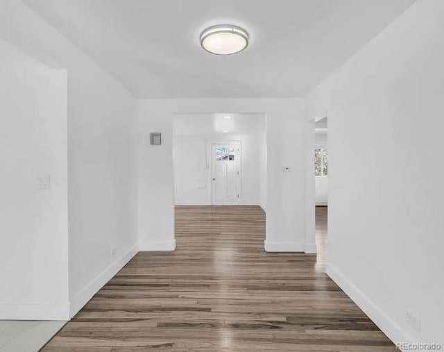 hall with visible vents, baseboards, and wood finished floors