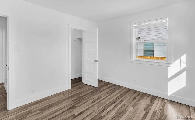 unfurnished bedroom with a closet, baseboards, and wood finished floors