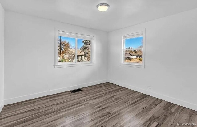 empty room with visible vents, baseboards, and wood finished floors