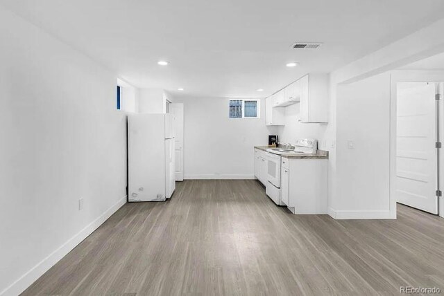 kitchen featuring white appliances, wood finished floors, visible vents, baseboards, and white cabinetry