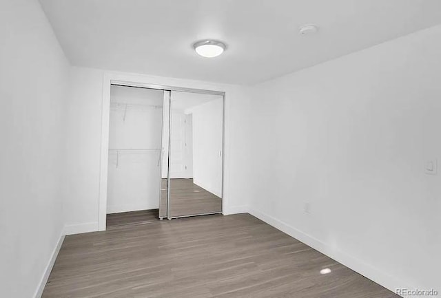 unfurnished bedroom with a closet, baseboards, and wood finished floors