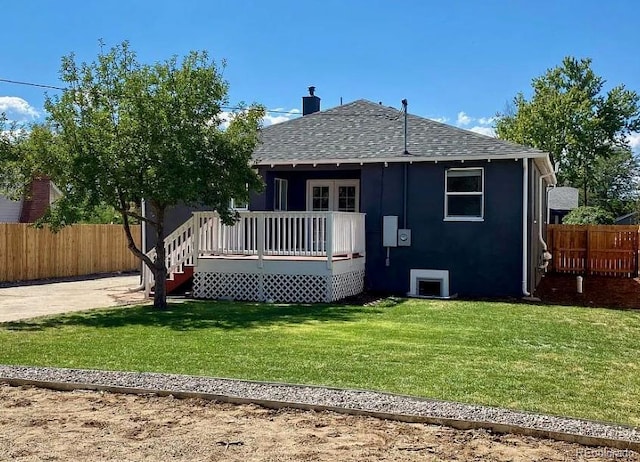 rear view of property with a yard, a shingled roof, a wooden deck, and fence