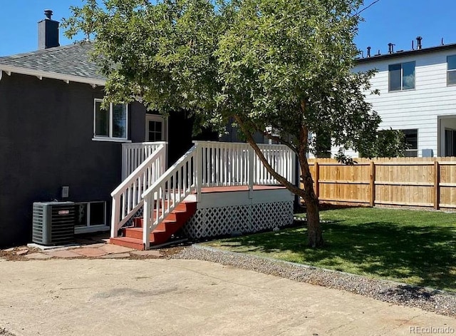 rear view of house featuring central AC, fence, a yard, a wooden deck, and a chimney