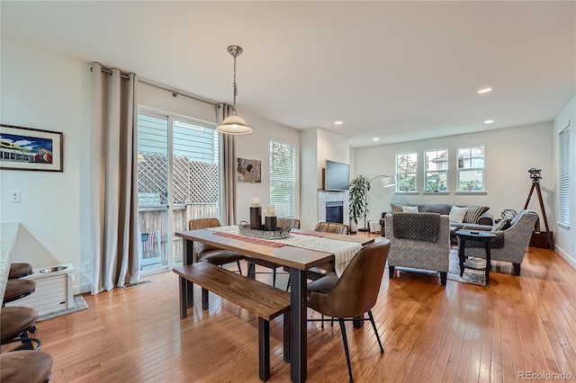 dining space with a tiled fireplace and light hardwood / wood-style floors