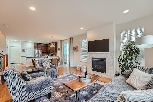 living room with a tile fireplace and light hardwood / wood-style flooring