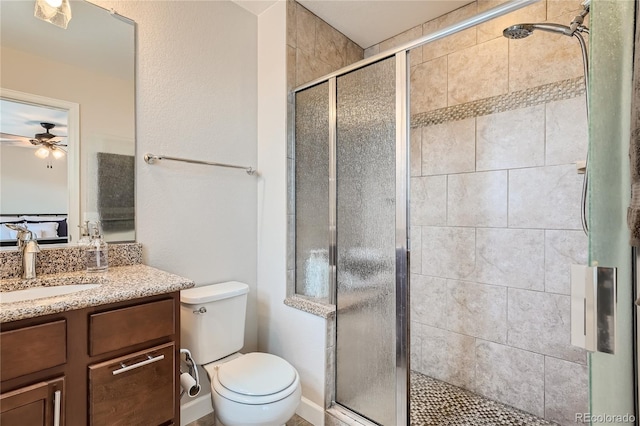 bathroom with vanity, ceiling fan, a shower with shower door, and toilet