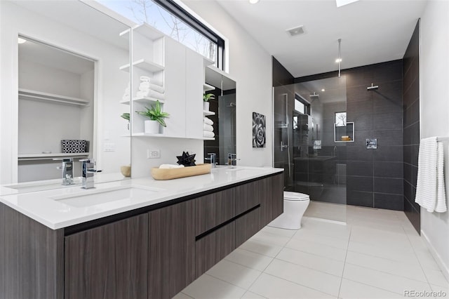 bathroom featuring tile patterned floors, toilet, vanity, and a tile shower