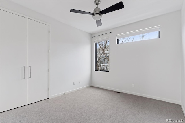 unfurnished bedroom featuring a closet, ceiling fan, light carpet, and multiple windows