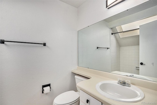 bathroom with tiled shower, vanity, and toilet