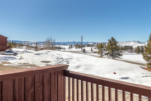 yard layered in snow with a mountain view and a balcony