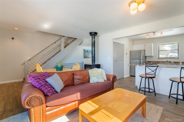 living room with light wood-type flooring, a wood stove, and baseboards