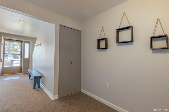 hallway featuring carpet flooring and baseboards