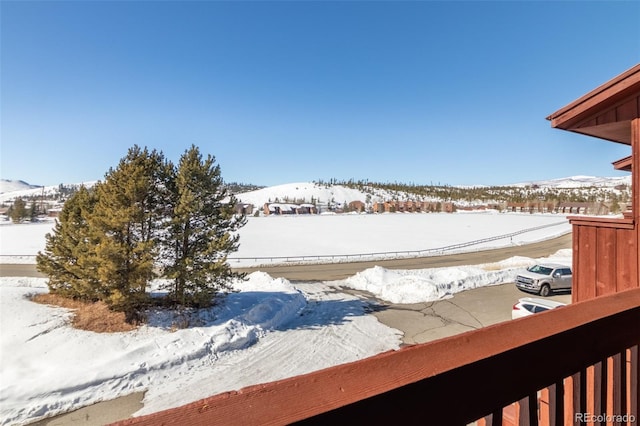 yard covered in snow featuring a mountain view