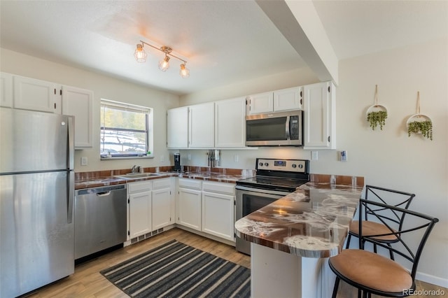 kitchen with appliances with stainless steel finishes, dark countertops, white cabinetry, and a peninsula