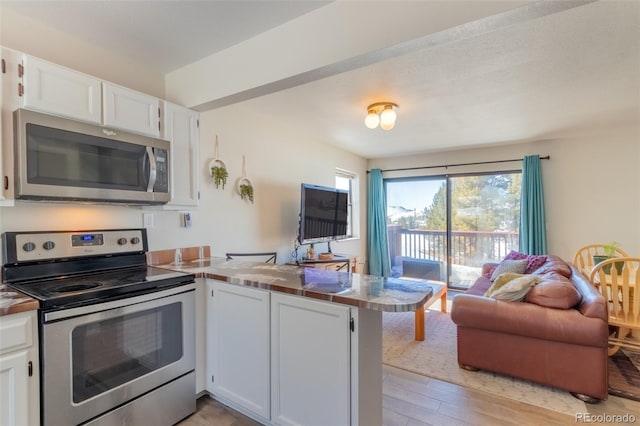 kitchen with light wood-style flooring, stainless steel appliances, a peninsula, white cabinets, and open floor plan