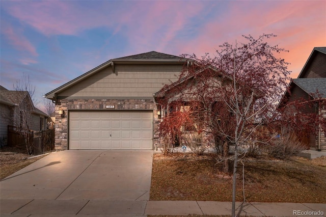 view of front of house featuring a garage, stone siding, and driveway