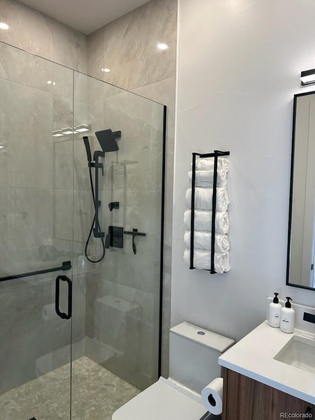 bathroom with vanity, a shower with shower door, and toilet