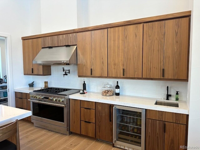 kitchen featuring sink, stainless steel appliances, wine cooler, light hardwood / wood-style flooring, and ventilation hood