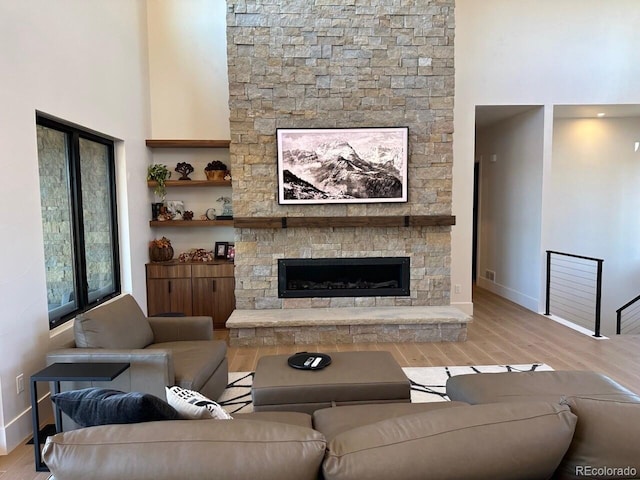 living room featuring a high ceiling, a fireplace, and light hardwood / wood-style flooring