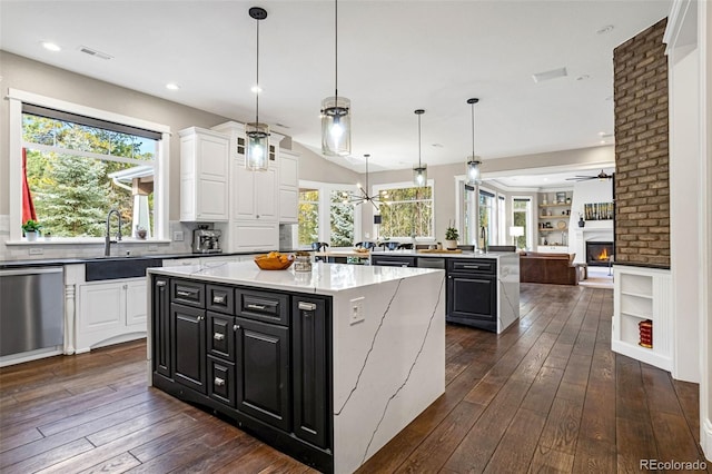 kitchen with sink, white cabinetry, a center island, stainless steel dishwasher, and pendant lighting