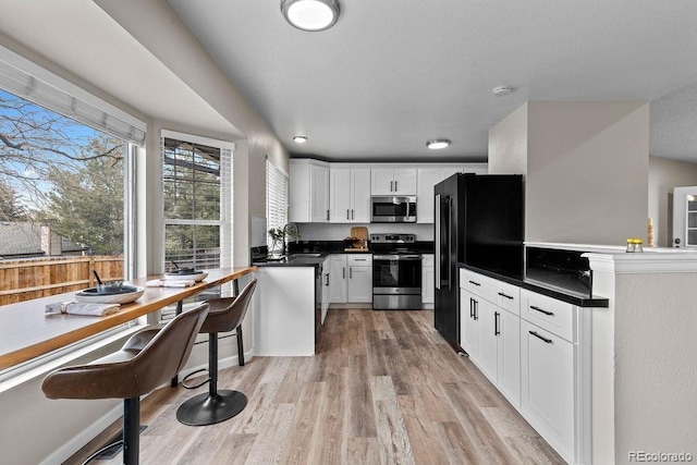 20908 E Dorado Cir, Centennial, CO 80015 - kitchen with stainless steel appliances, a sink, white cabinetry, light wood-style flooring, and dark countertops