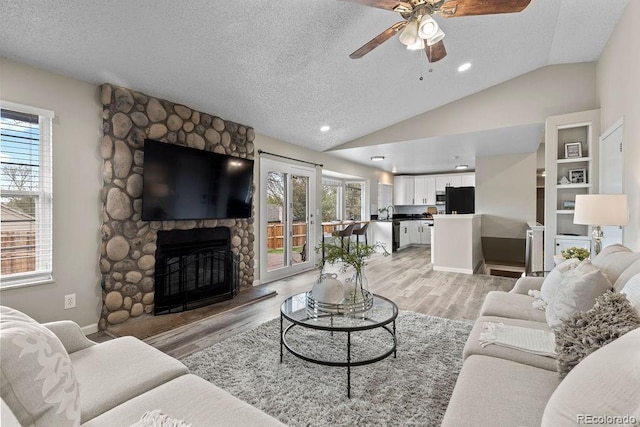 20908 E Dorado Cir, Centennial, CO 80015 - living area with ceiling fan, lofted ceiling, a stone fireplace, light wood-type flooring, and a textured ceiling