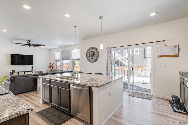 kitchen featuring pendant lighting, sink, light stone countertops, an island with sink, and stainless steel dishwasher