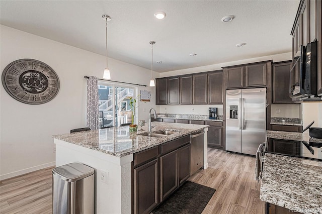 kitchen featuring a kitchen island with sink, sink, hanging light fixtures, and appliances with stainless steel finishes