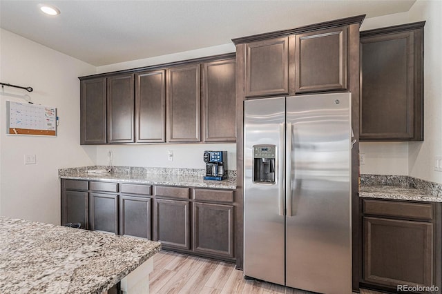 kitchen with dark brown cabinetry, stainless steel fridge, and light hardwood / wood-style floors