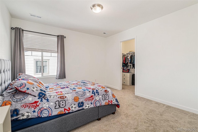 bedroom with light carpet and a spacious closet