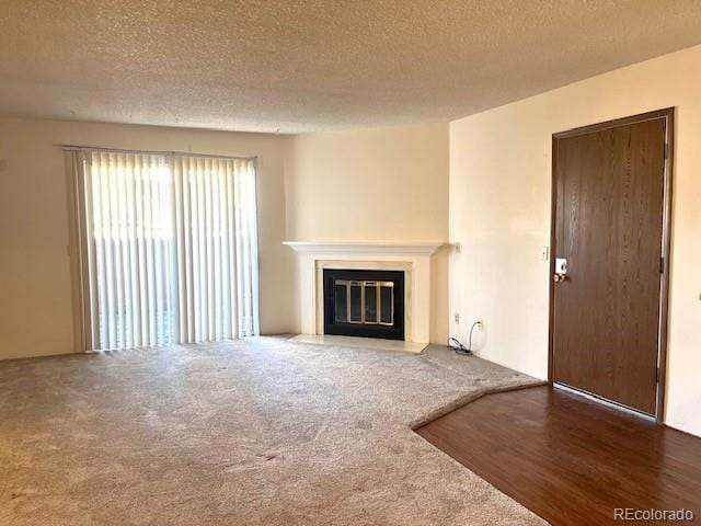 unfurnished living room with dark carpet and a textured ceiling