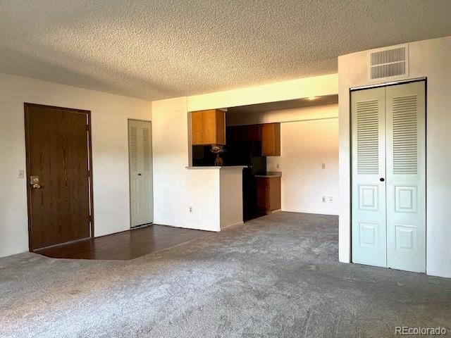 interior space featuring dark carpet and a textured ceiling