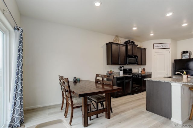 kitchen featuring light wood-style flooring, dark brown cabinetry, recessed lighting, light stone countertops, and black appliances