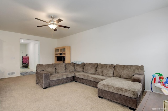 carpeted living area featuring visible vents and a ceiling fan