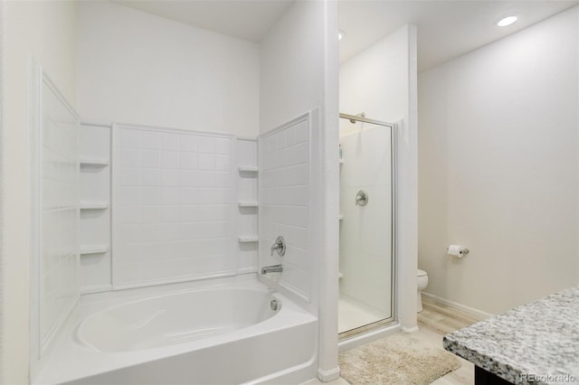 full bath featuring a tub to relax in, a stall shower, toilet, wood finished floors, and vanity