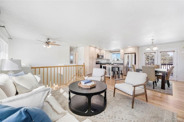 living room featuring sink, a textured ceiling, and light hardwood / wood-style flooring