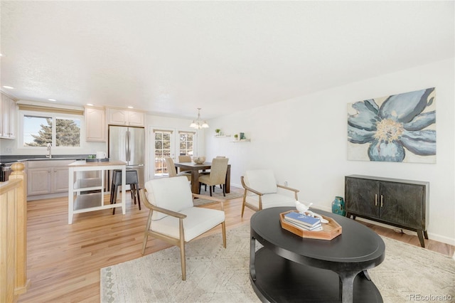 living room with sink, light hardwood / wood-style flooring, and a notable chandelier