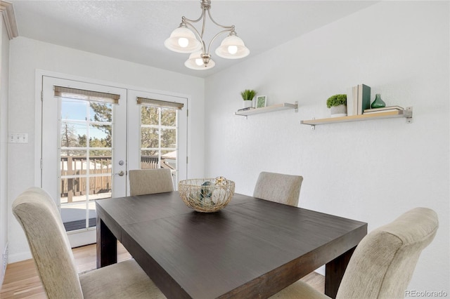 dining area with french doors, a chandelier, and light wood-type flooring